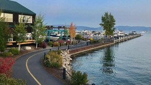 A waterfront property with a paved walkway, a dock, and boats in the background. - Pet Friendly with Big Views! (Tahoe City)