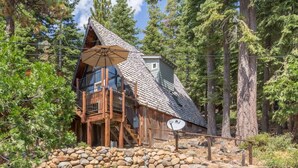 A cabin with a wooden deck, a satellite dish, and a stone foundation. - Pet Friendly with Big Views! (Tahoe City)