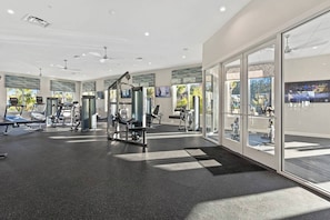 A modern gym with various exercise equipment, large windows, and a view of the outdoors.