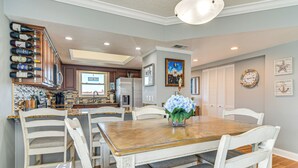 A dining area with a wooden table, white chairs, and a vase of flowers. - Pool, Beach Access: Waterfront Treasure Island Gem (Treasure Island)