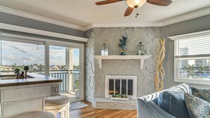 A spacious living area with a stone fireplace, a bar with stools, and a view of the city through large windows. - Pool, Beach Access: Waterfront Treasure Island Gem (Treasure Island)