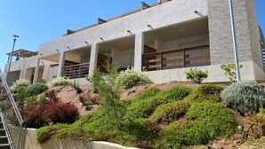 A modern building with multiple balconies, a stone facade, and landscaped gardens. - Une Pause... Quelque Part en Tout Compris (Linguizzetta)