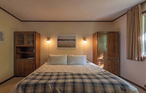 Ein Schlafzimmer mit einem Bett, zwei Schränken, einem Nachttisch und einem gerahmten Bild an der Wand.