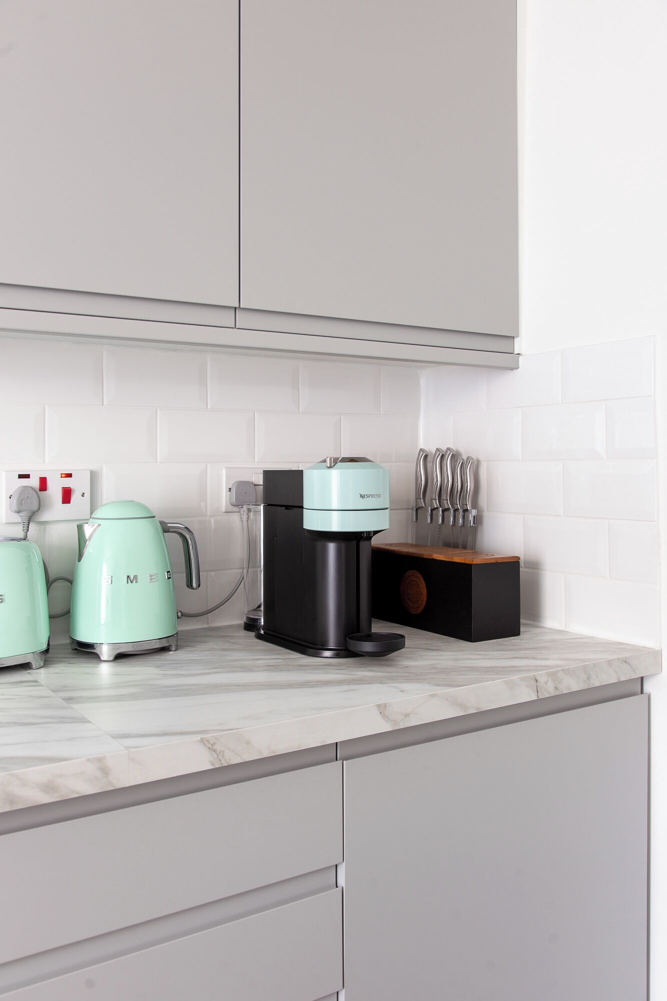 Een keuken met witte kasten, een koffiezetapparaat, een waterkoker en een messenblok.