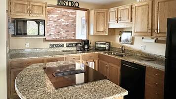 A kitchen with wooden cabinets, a granite countertop, a coffee machine, a toaster, and a refrigerator.