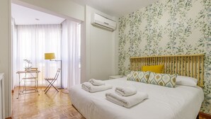A bedroom with a bed, a desk, and a chair.