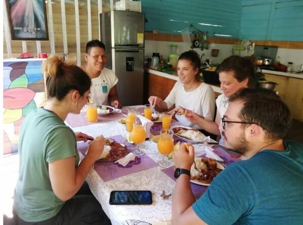 Guests can enjoy meals together in this communal dining area, surrounded by a colorful mural and equipped with a kitchen.