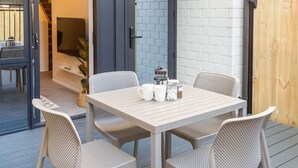 Eine Terrasse im Freien mit Tisch und Stühlen, einer Holzterrasse und einer Backsteinmauer.