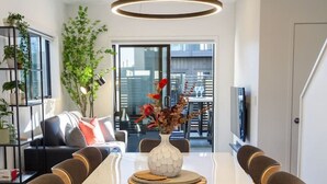 A modern dining area with a long table, chairs, and a vase with flowers.