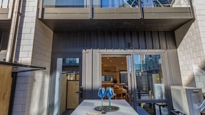 A modern two-story building with a balcony, a dining area with outdoor seating, and a view of the interior.