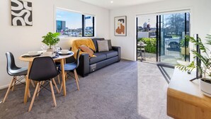 Ein modernes Wohnzimmer mit Essbereich, einer Couch und einem Balkon mit Pflanzen.