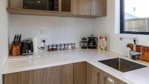 Eine moderne Küche mit Holzschränken, einer weißen Arbeitsplatte, einer Kaffeemaschine, einem Toaster und einem Fenster mit Blick.