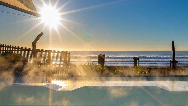 A hot tub with a view of the ocean and a clear sky.