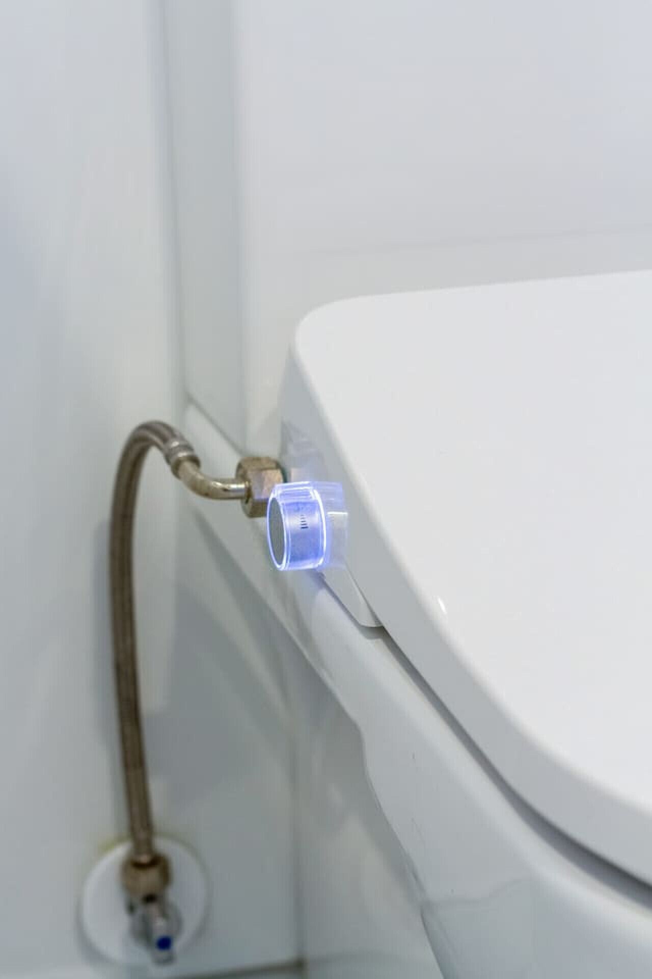 WC-istuin, jossa näkyvä putkiliitäntä ja joustava letku.