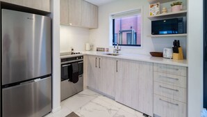 A modern kitchen with stainless steel appliances, light wood cabinets, and a window providing natural light.