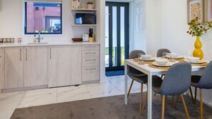 A modern kitchen with white cabinets, a marble countertop, and a dining area with a table set for four.