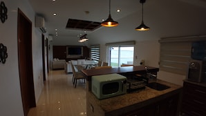A modern kitchen with a dining area, a microwave, and a water dispenser. - Bartolome Oceanfront Suites (Isla Mujeres)