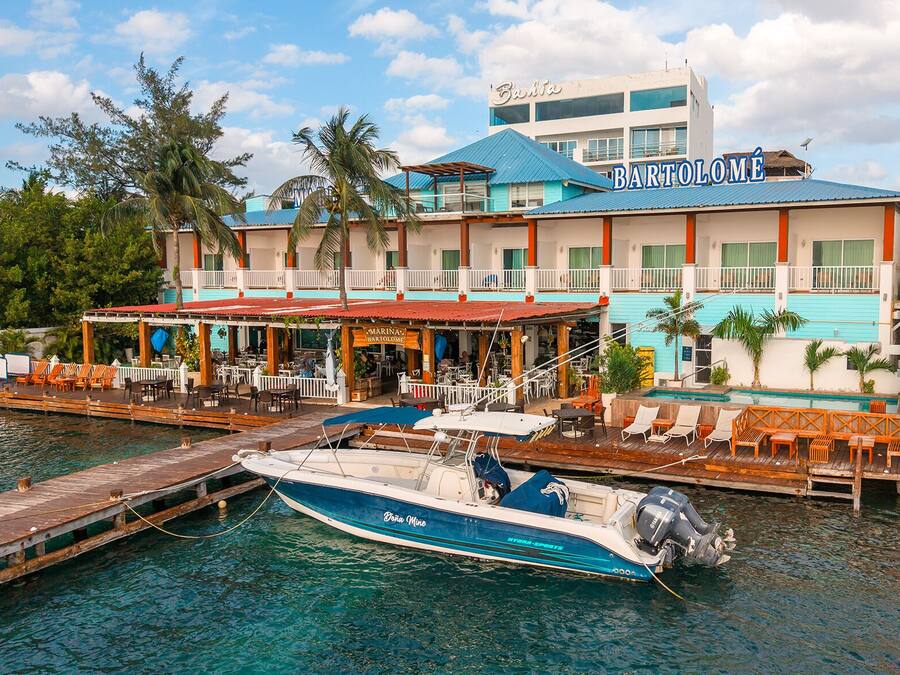 A waterfront hotel with a dock, a boat, and outdoor seating areas.