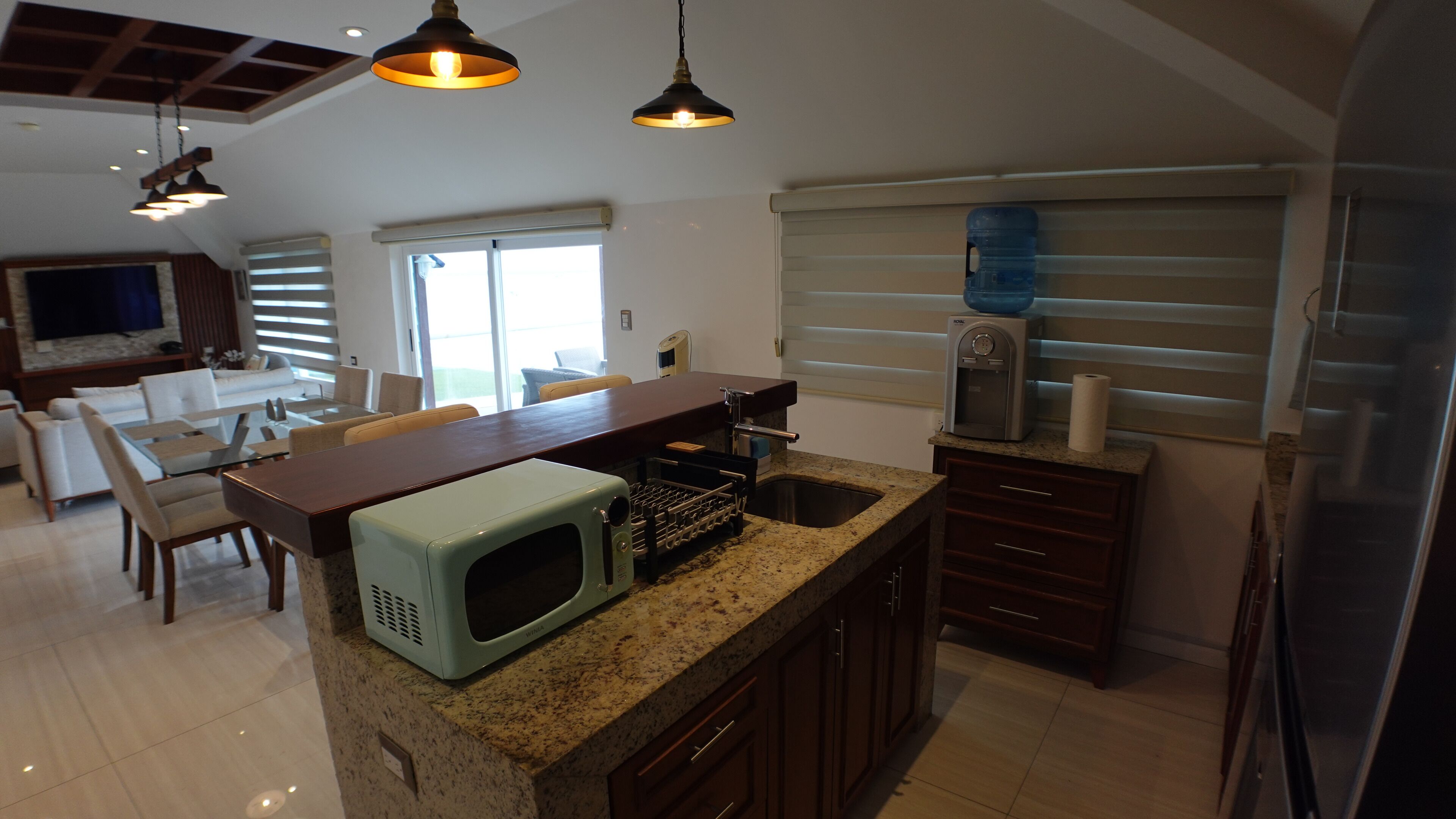 A kitchen with granite countertops, a built-in microwave, a water dispenser, and a refrigerator.