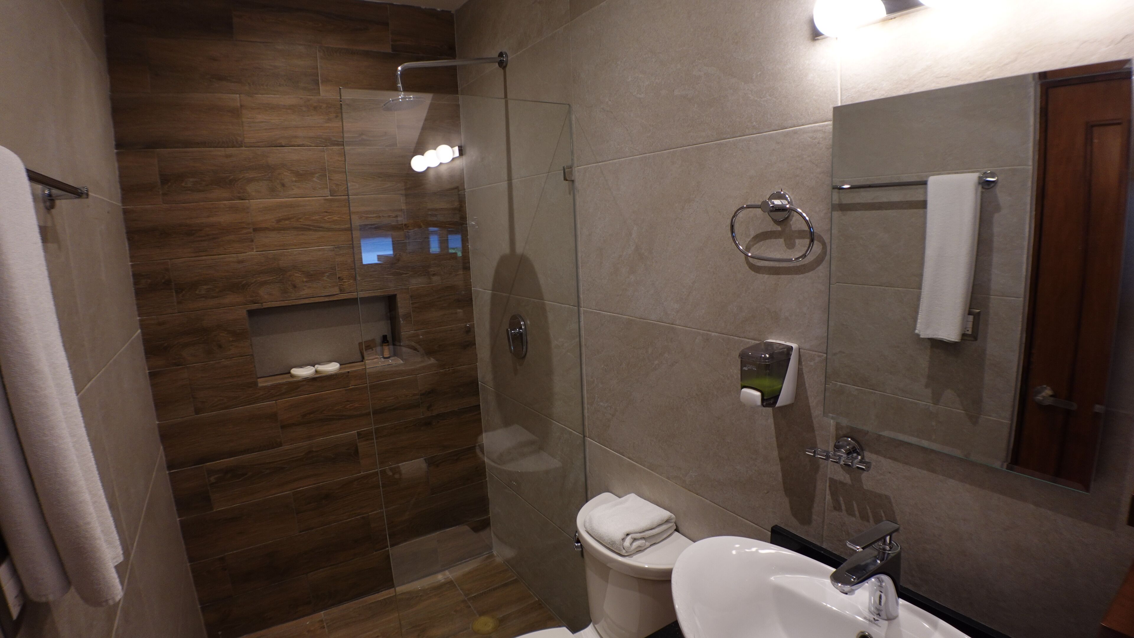 Une salle de bain moderne avec une douche à parois de verre, des toilettes, un lavabo et un miroir.