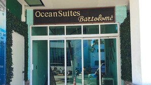 The entrance to OceanSuites Bartolomé with a glass door and a small outdoor area with a mat. - Bartolome Oceanfront Suites (Isla Mujeres)