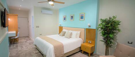Ein Schlafzimmer mit Bett, Nachttischen, Schreibtisch, Stuhl, Deckenventilator und einer Topfpflanze.