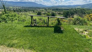 A picnic table in a grassy field with a scenic view of distant hills and mountains. - Superbe Propriété Avec vue Imprenable, Piscine, jeu de Boules au Cœur du Luberon (Saint Saturnin lès Apt)
