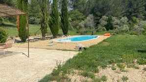 A swimming pool surrounded by a gravel area with a wooden deck and lounge chairs. - Superbe Propriété Avec vue Imprenable, Piscine, jeu de Boules au Cœur du Luberon (Saint Saturnin lès Apt)