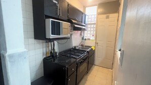 A compact kitchen with a microwave, stove, and cabinets.
