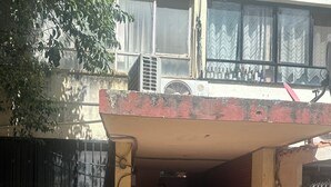 A residential building with a covered entrance, potted plants, and a tiled walkway.