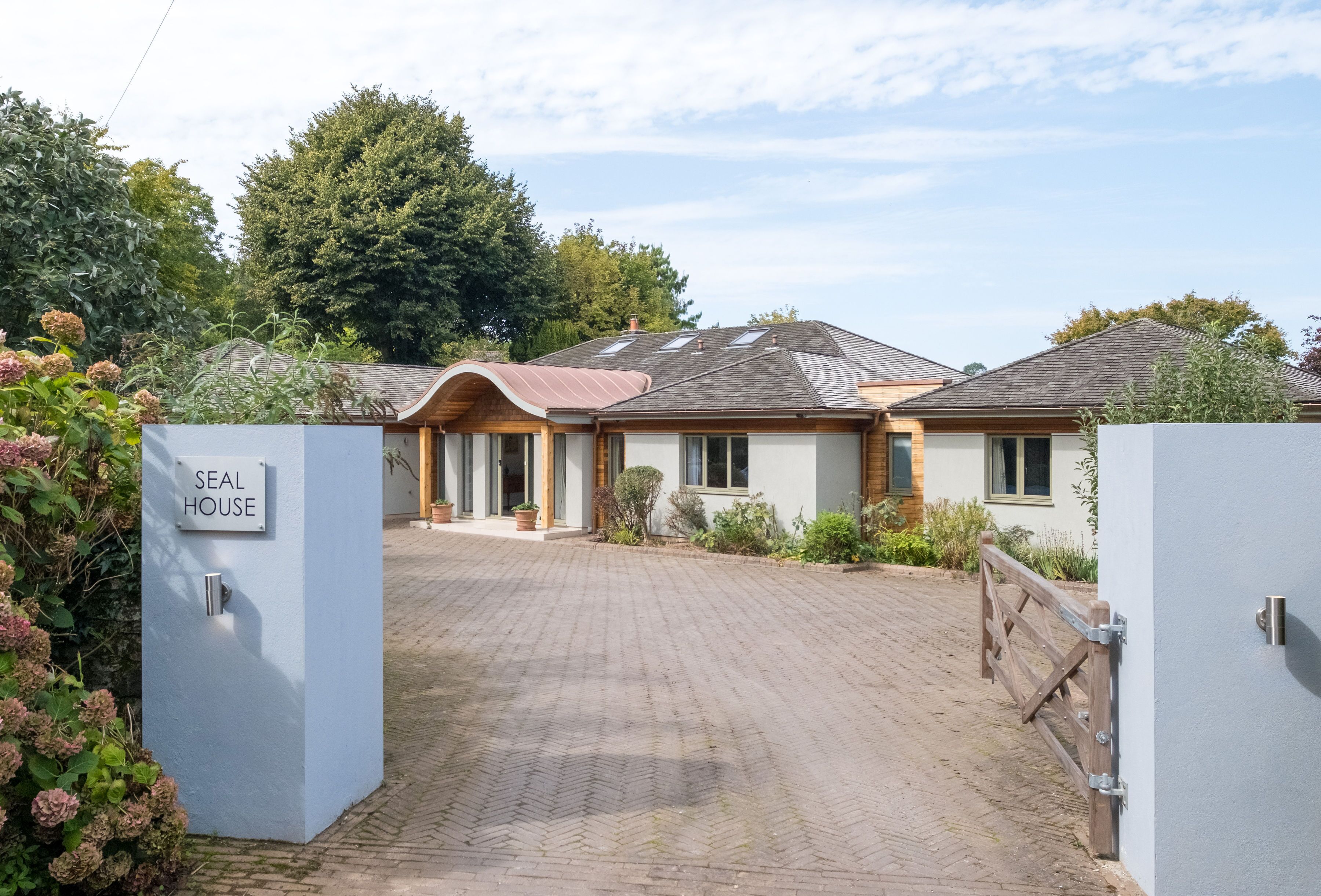 Een woonhuis genaamd "Seal House" met een verharde oprit en een houten poort.