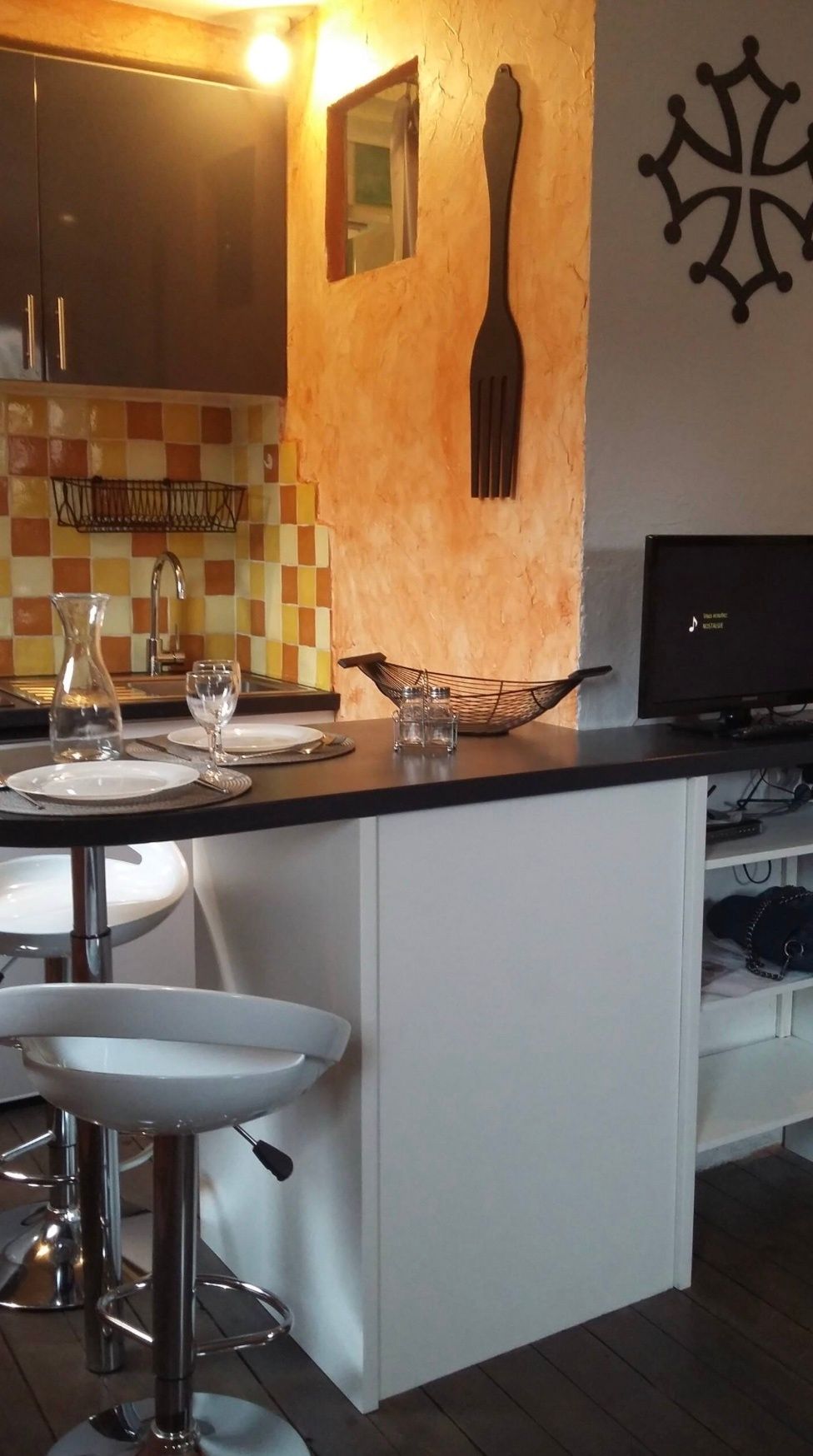 A kitchen with a bar area, a sink, and a television.