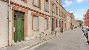 Eine Straße mit Gebäuden im traditionellen Stil, einer grünen Tür und geparkten Autos.