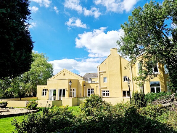 A yellow building with multiple windows and a well-maintained garden.