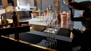 Una zona de bar con encimera negra, una bandeja dorada y varias copas de vino.