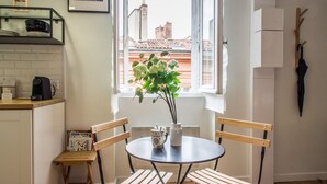 A small kitchen with a window, a table with chairs, and a vase with flowers.