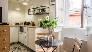 A modern kitchen with white cabinets, a black countertop, and a window with a view of buildings.