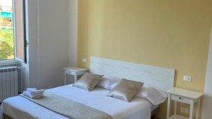 Ein Schlafzimmer mit einem Bett, Nachttischen, einem Fenster und einer Klimaanlage.
