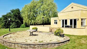 A house with a stone circular patio, a table, and a chair.
