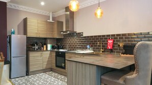 A modern kitchen with wooden cabinets, a black tiled backsplash, and pendant lighting. - Alexander (Preston)
