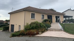 A single-story house with a tiled roof, a front entrance with a door, and a small porch area.