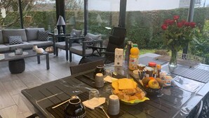 A breakfast setup on an outdoor patio with a table, chairs, and a sofa.