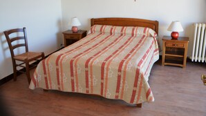 A bedroom with a bed, two bedside tables, a chair, and a radiator. - Bel Appartement T2 Avec Balcon Donnant Plein sud sur la Chaîne des Pyrénées (Font-Romeu-Odeillo-Via)