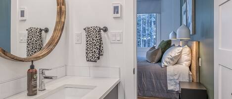 A modern bathroom with a large mirror, two leopard print towels, a bottle of hand soap, and a white sink.
