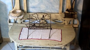 A rustic wooden shelf unit with decorative items, a small table with a crocheted placemat, and a wall-mounted shelf with a vase and a green box. - A casa di Oba, vacation home a stone's throw from the sea in Nora, Pula, Sardinia (Pula)