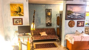 A cozy room with a sofa, a desk with a lamp, a bed, and various wall decorations including paintings and a lamp. - A casa di Oba, vacation home a stone's throw from the sea in Nora, Pula, Sardinia (Pula)