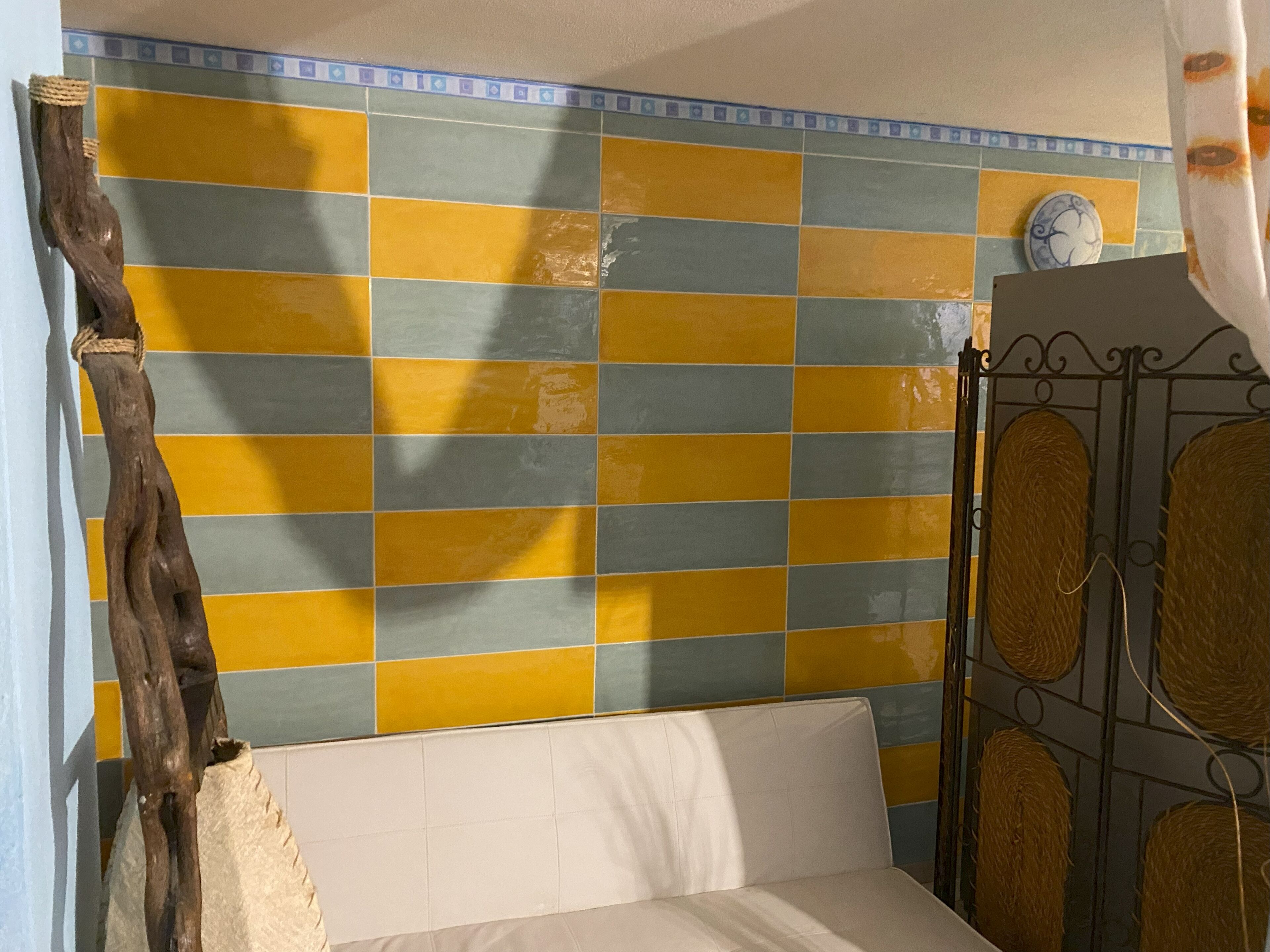 A room with a bed, a tiled wall, and a metal gate.