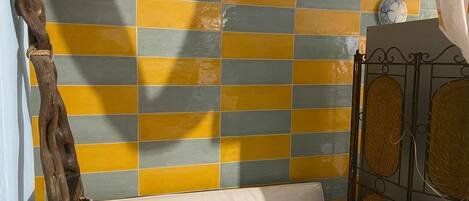 A room with a bed, a tiled wall, and a metal gate.