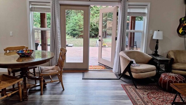 A dining area with a round table and chairs, a sofa, and a rug. - Cottage/Studio in Cobble Hill Village - hiking, wineries and more (Cobble Hill)