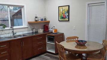 A compact kitchen with wooden cabinets, a built-in oven, and a dining table with chairs.